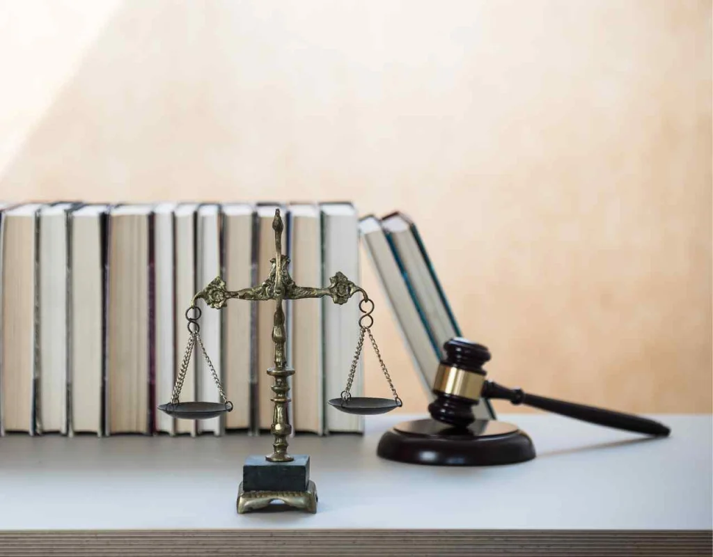 Scale and mallet and gavel in front of a row of books